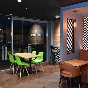 a restaurant with green chairs and a wooden table