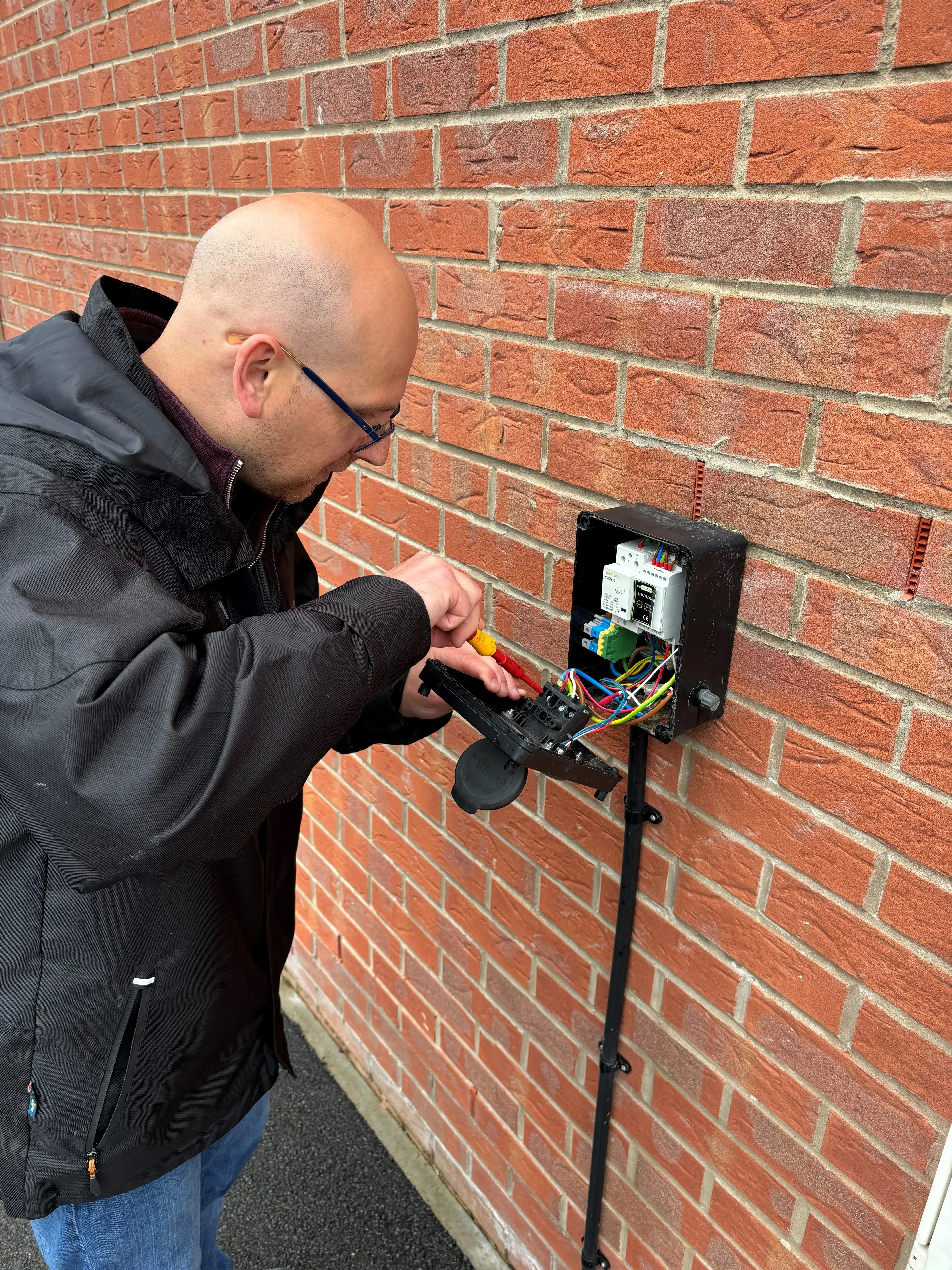 man in a black jacket fixing a power outlet