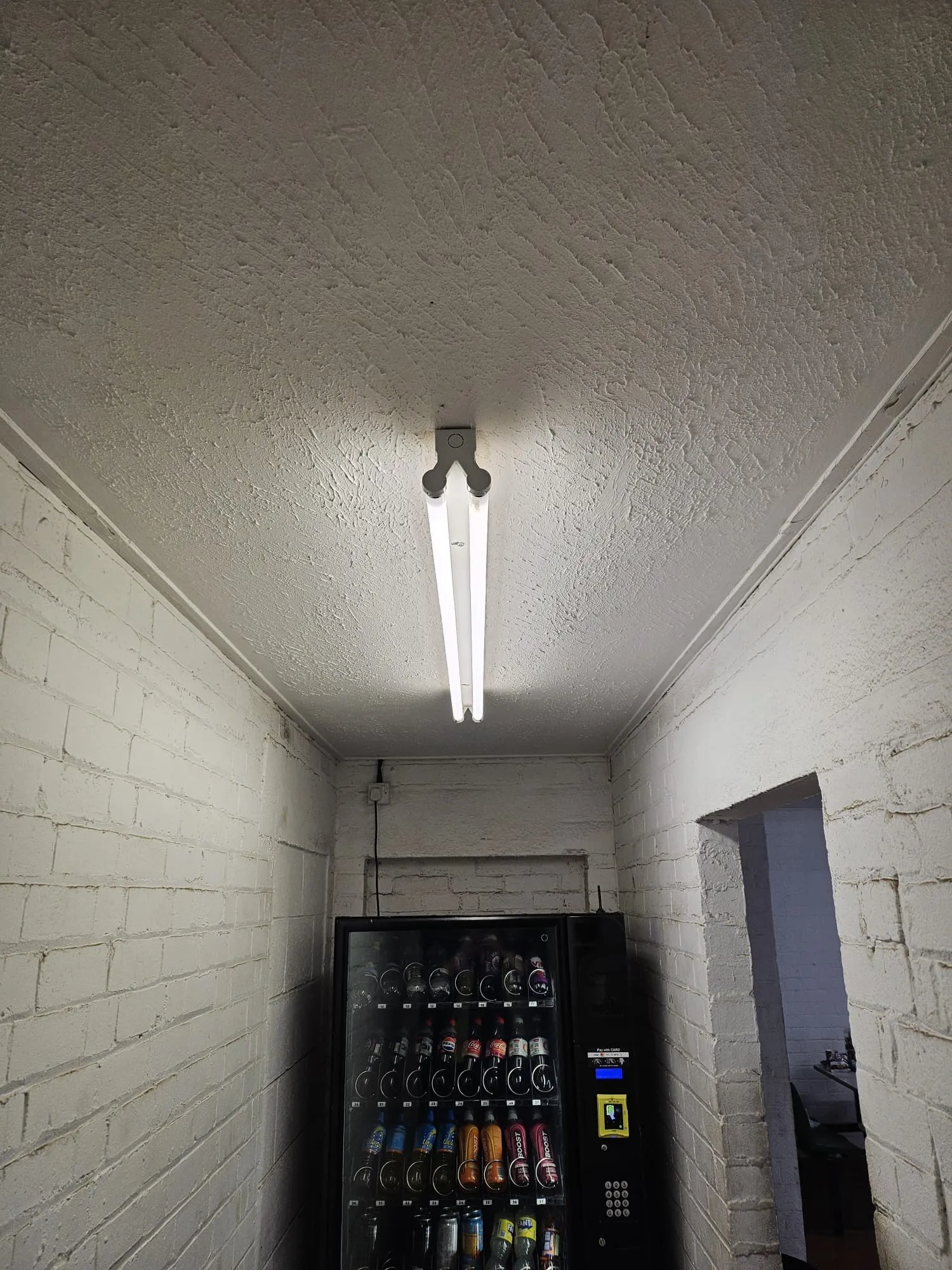 A vending machine in a white brick wall.