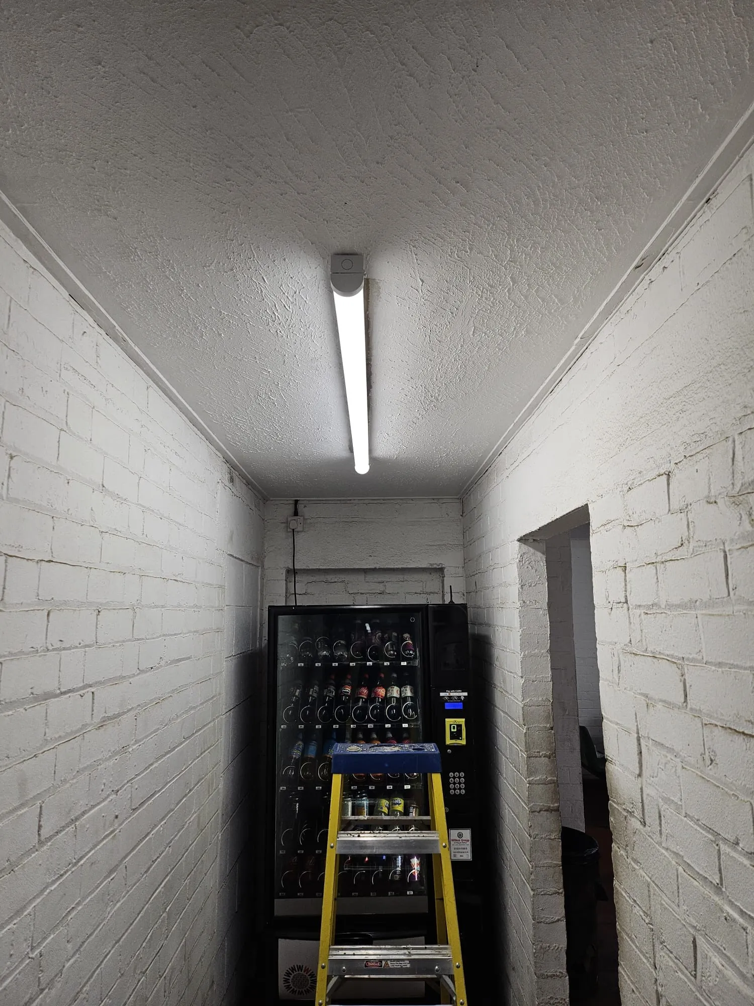A yellow ladder going up a white brick wall.