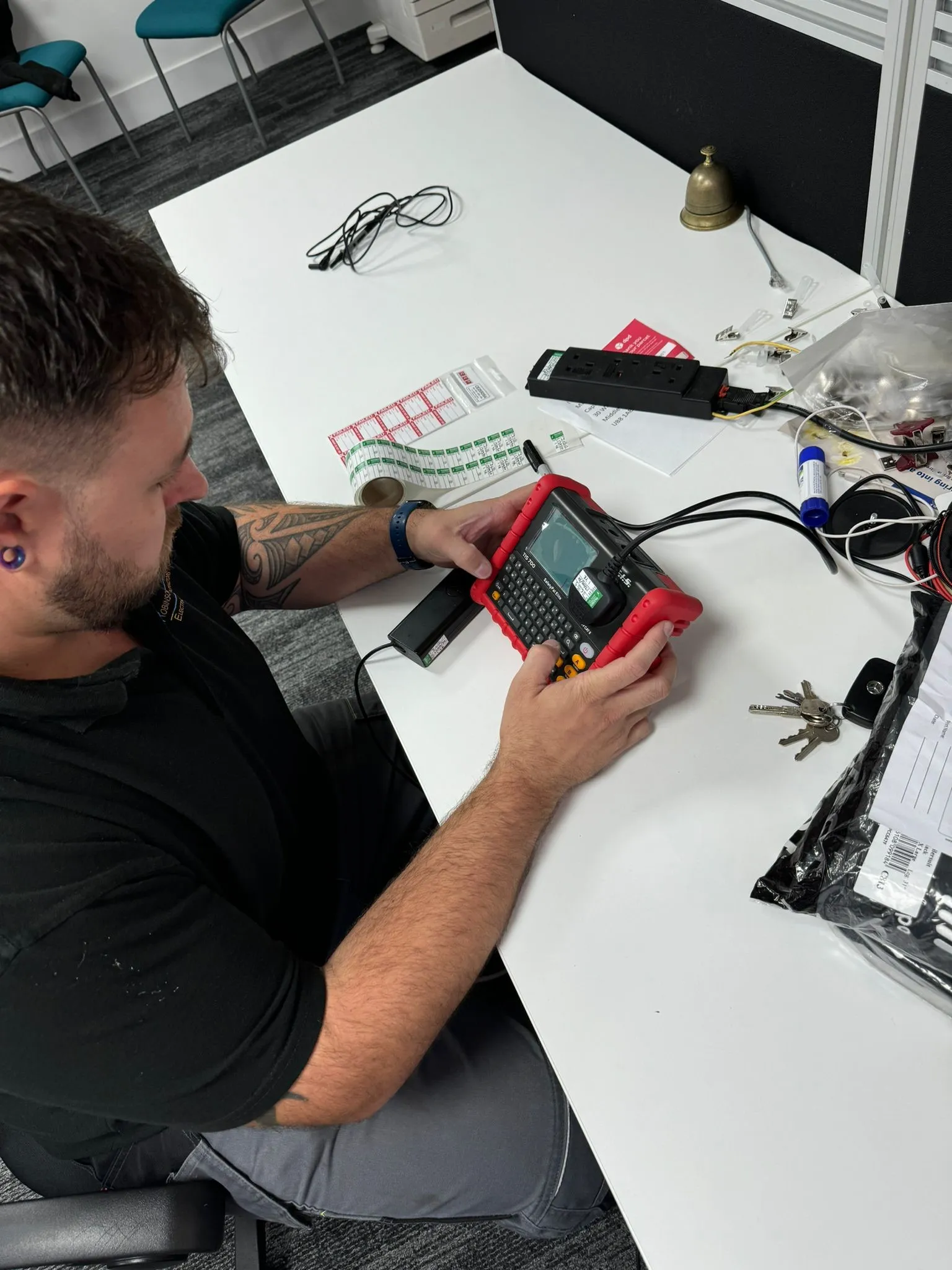 man sitting at a table with a multimeter in his hand