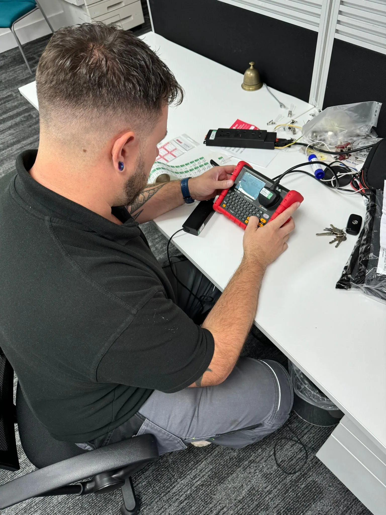 man sitting at a desk with a laptop and a multimeter