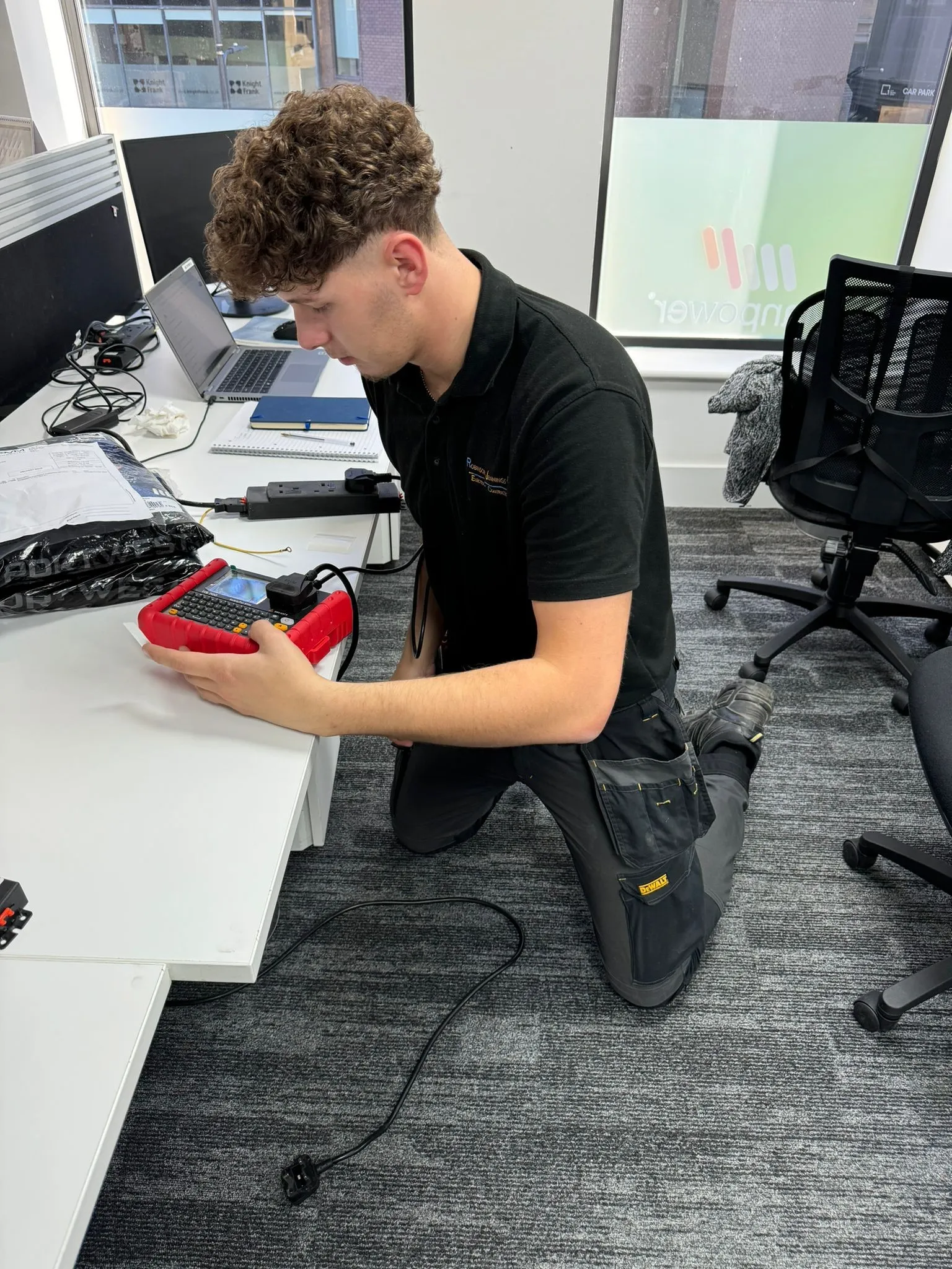 man kneeling on the floor with a red and black device