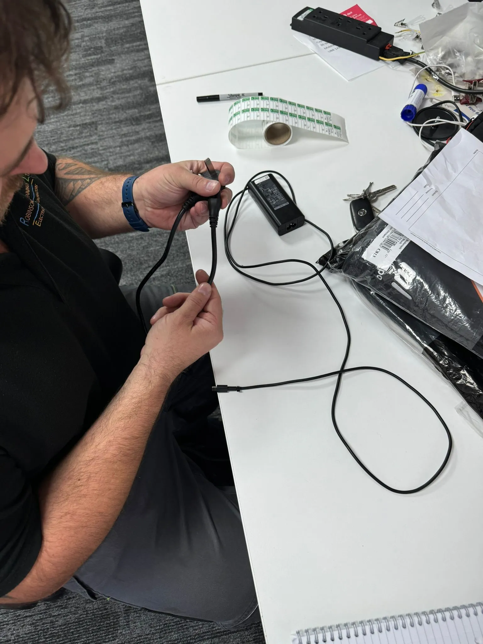 man sitting at a table with a cell phone and wires