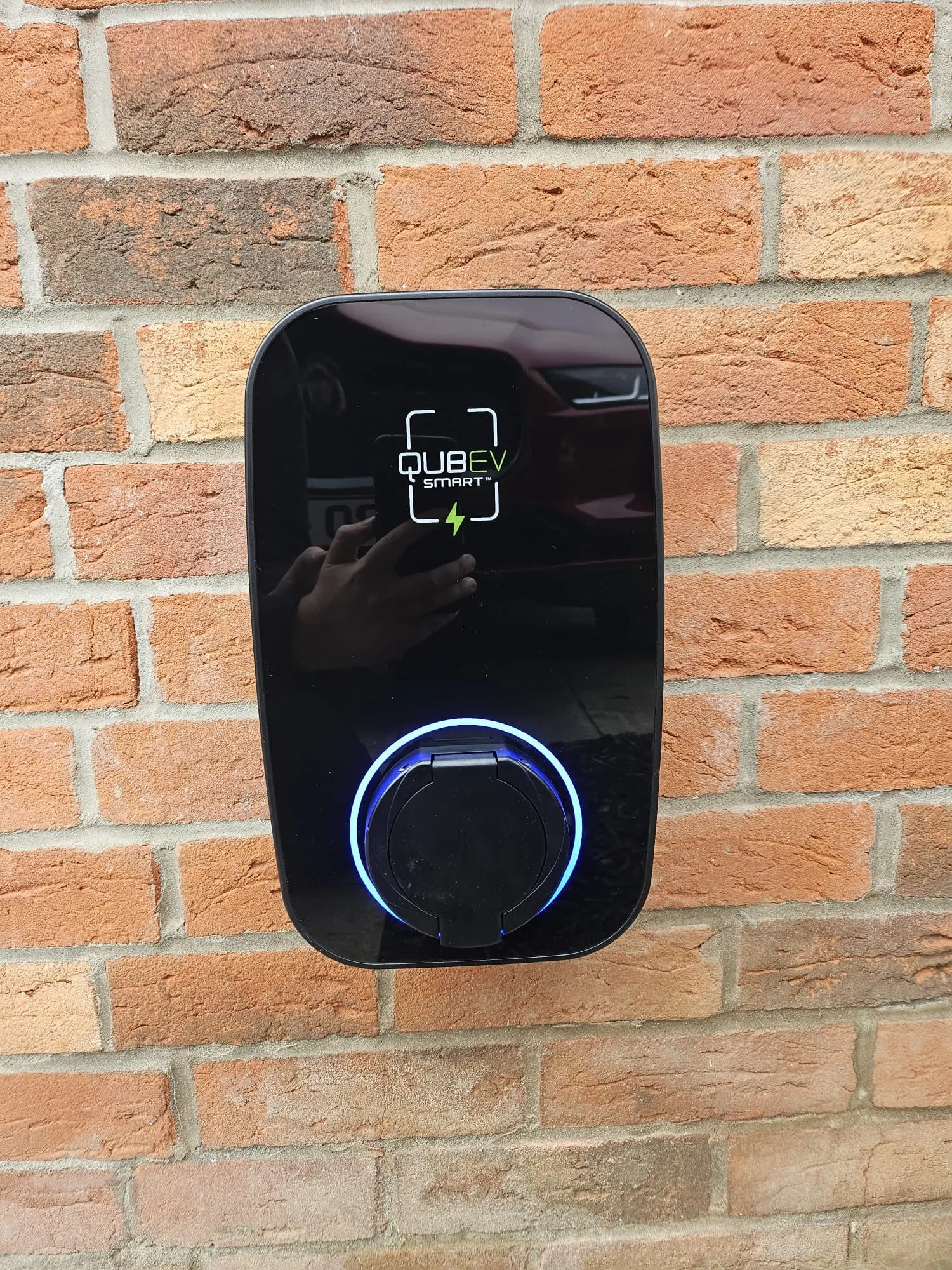 A smart phone mounted to a brick wall.