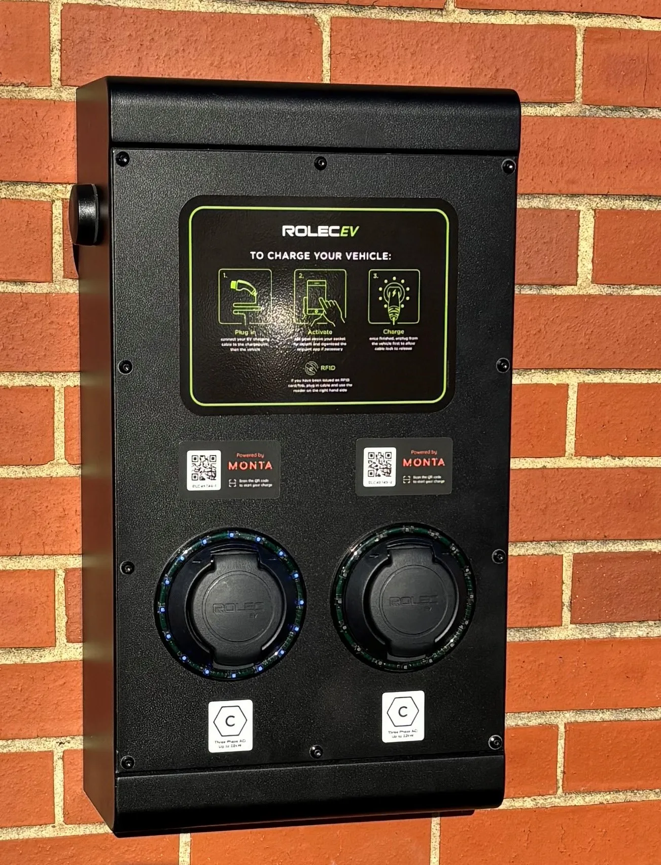 A close up of a black box on a brick wall.
