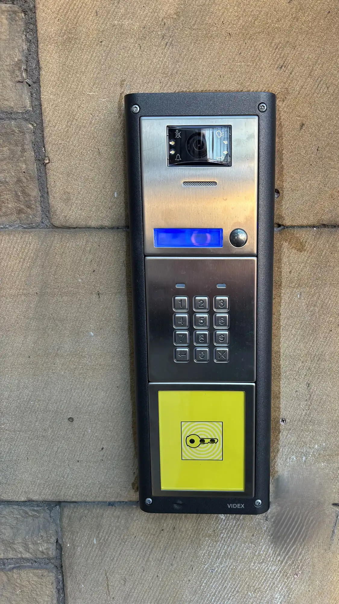 An electronic device attached to a brick wall.