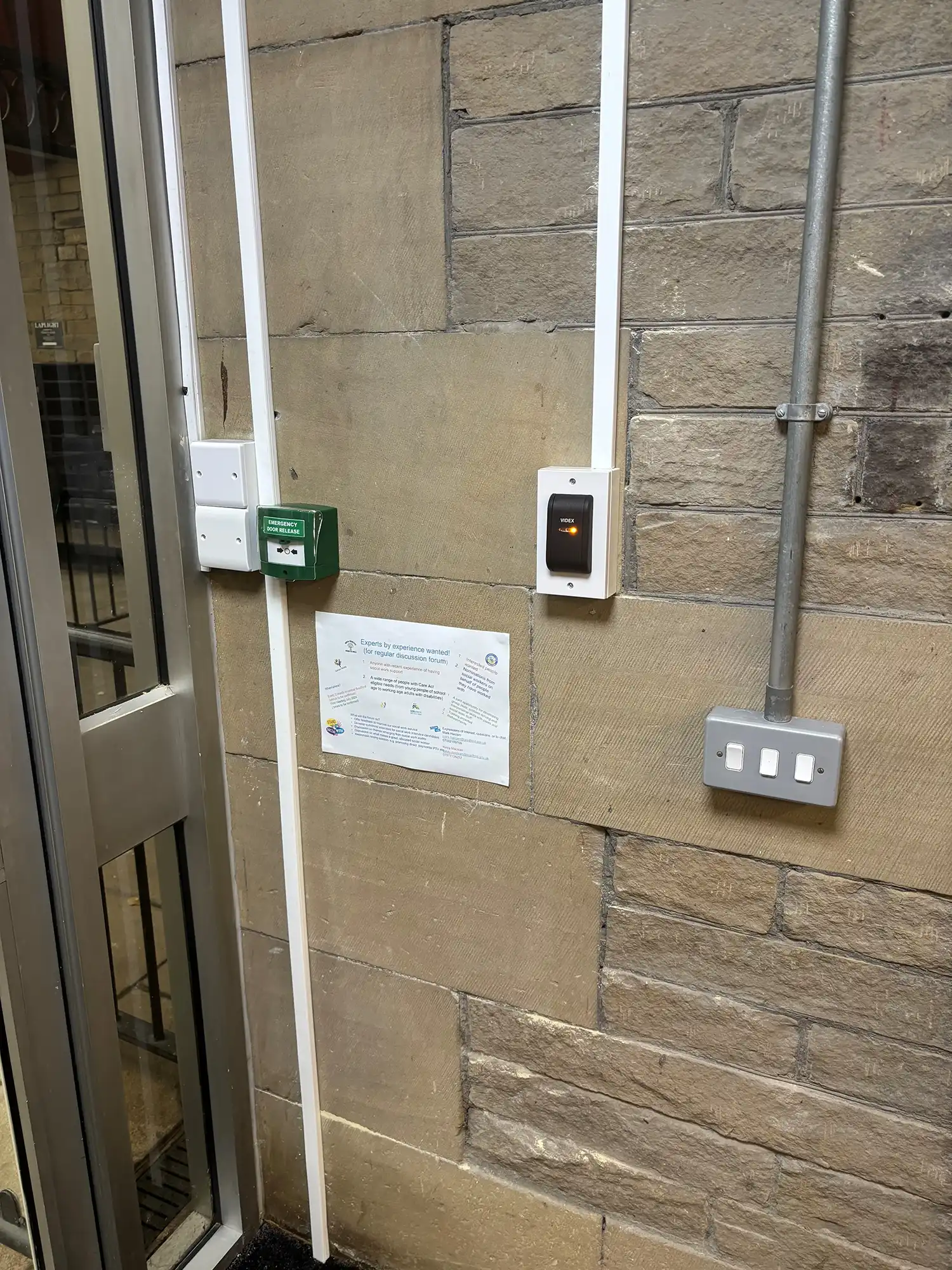 A door with a sign on it next to a brick wall.
